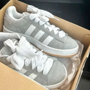 Adidas Campus 00 - Säljer mina Adidas campus 00 i grå.  Dem är i bra skick (ca 8/10) Har ej kvar orginallådan men de vita och gråa banden kommer med. Dem är normala i storleken. Säljer billigt då jag gärna vill få dem sålda.