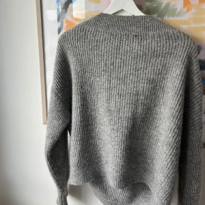 Grå stickad tröja - Säljer en supermysig grå stickad tröja. Den är perfekt för kyliga dagar och har en normal passform. Tröjan har långa ärmar och är ribbstickad vilket ger den en snygg textur. Perfekt för höst och vinter! 🧶 V ringad också