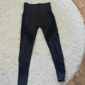 Svarta leggings - Säljer ett par grå träningstights i bra skick. De är högmidjade och har en tight passform. Perfekta för träning eller vardagsbruk. Materialet är stretchigt och bekvämt.