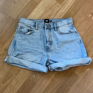Ljusblå jeansshorts från 157 - Säljer ett par ljusblå jeansshorts från 157. De är i nyskick och har en normal passform. Shortsen är uppvikta vid benen för en avslappnad look. Perfekta för sommaren!