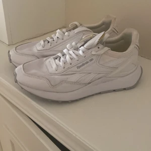 Vita sneakers från Reebok - Snygga vita sneakers från Reebok med klassisk design och snörning. Skorna har en bekväm sula och Reebok-loggan på sidan och hälen. Perfekta för en stilren look.