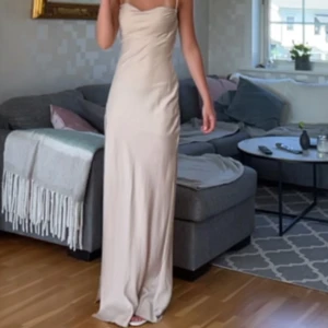 Balklänning - Champagnefärgad balklänning. Klänningen har en öppen rygg med knytband så man kan justera den. Jag har sytt upp den och sytt in den där fram. Den har en slitts på ena sidan. Är i storlek 36 men passar mig som har 34 i vanskliga fall, jag är 166 cm och den är bra läng med klackar. Priset kan diskuteras 