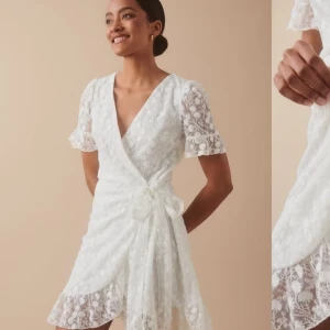 Vit spetsklänning med volangdetaljer - Säljer en söt vit spetsklänning med omlott-design och volangdetaljer från Gina tricot, då den är lite för liten. Klänningen har korta ärmar och en v-ringad hals. Perfekt för somriga dagar eller speciella tillfällen. 💫 endast använd fåtal gånger, som ny! Nypris 699kr, Skriv om ni har frågor💗