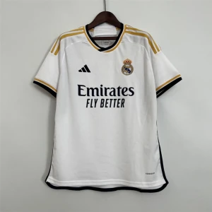 Real Madrid Hemmamanströja 23/24 - Produktbeskrivning: Officiell Real Madrid tröja för säsongen 2023/2024. Tröjan är helt ny och har aldrig använts. Finns i alla storlekar. Du kan välja spelarens namn och nummer. Du kan även lägga till La Liga- och Champions League-märken. Tröjan har en snygg design med guldfärgade ränder på axlarna och ärmarna, samt Real Madrids märke och Adidas-logotypen på bröstet. Tillverkad av bra material för att ge bästa komfort och prestanda.