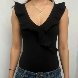 Svart body från H&M - Snygg svart body från H&M med volangdetaljer