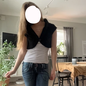 Svart stickad bolerotopp - Säljer en svart stickad bolerotopp med korta ärmar och en stor knapp framtill. Perfekt för att lägga till en extra touch till din outfit. Passar bra över en enkel topp eller klänning och perfekt till vardagliga outfits🩷🩷😋
