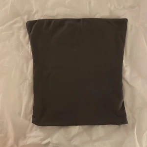 Grå tubtopp från BikBok - Snygg grå tubtopp från BikBok i storlek S. Perfekt för en stilren look och enkel att matcha med olika outfits. Ett måste inför sommaren!