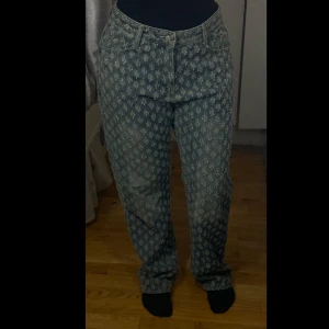 Mönstrade jeansbyxor - Snygga jeansbyxor med unikt mönster i blått och vitt. Byxorna har en klassisk femficksdesign och knappgylf. Perfekta för dig som vill sticka ut med en cool stil.