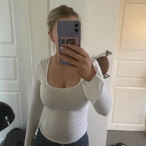 Vit långärmad topp från Gina Tricot - Säljer en stilren vit långärmad topp från Gina Tricot i storlek XS. Toppen har en rund halsringning och är perfekt för lager-på-lager eller att bära som den är. Slits vid ärmarna 