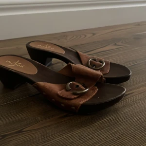 Bruna sandaler med klack och spänne - Snygga bruna sandaler med klack och dekorativt spänne. Perfekta för en stilren look med en touch av elegans. Passar bra till både jeans och klänning.
