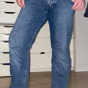 Blå jeans från Lee - Snygga blå jeans från Lee med klassisk femficksdesign och en bekväm passform. De har en knappgylf och är perfekta för en avslappnad stil. Märkeslappen i läder på baksidan ger en autentisk touch.