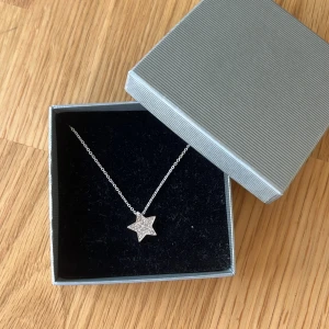 Silverhalsband med stjärnhänge från Guldfynd - Silverhalsband från Guldfynd med ett glittrande stjärnhänge. Hänget är dekorerat med små stenar som gnistrar i solljuset. Säljer det då jag inte använder silver. Oanvänt och kommer i sin orginalbox.