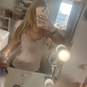 Ljusrosa linne med spetsdetaljer - Säljer ett ljusrosa linne med smala axelband och vacker spetsdetalj vid halsringningen. Linnet har ett diskret randigt mönster och är perfekt för en somrig look. Passar bra till jeans eller kjol för en avslappnad stil. Linnet har en liten fläck på framsidan men inget man tänker på o verkligheten. Pris går att diskuteras. Skriv för fler bilder 💕💕