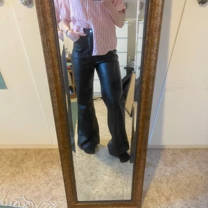Svarta skinnbyxor - Snygga svarta skinnbyxor med hög midja och bootcut-stil. Riktigt snygga och passar med både skjorta och blus. Obs!!! Inte äkta skinn! 