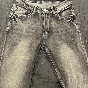 Grå jeans med slitningar - Snygga grå jeans med en cool tvättad look och diskreta slitningar. De har en klassisk femficksdesign och knappgylf. Perfekta för en avslappnad stil.