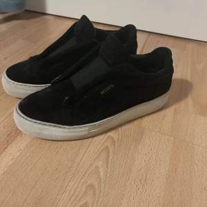 Snygga svarta sneakers från Axel Arigato i mocka med en stilren design. Skorna har en vit sula som ger en fin kontrast och en diskret logga på sidan. Perfekta för en trendig look.