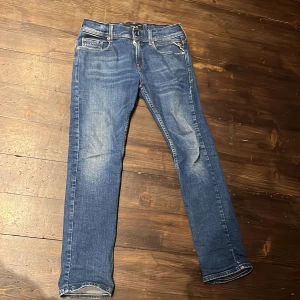 Slim blå jeans från Replay - Snygga blå jeans från Replay med klassisk femficksdesign och en bekväm passform. De har en dragkedja och knapp framtill samt Replay-logga på bakfickan. Perfekta för en avslappnad stil.