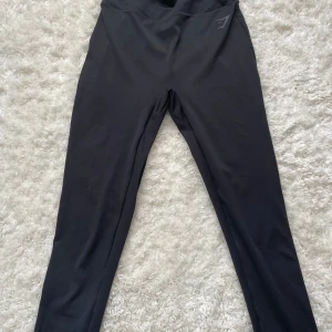 Svarta leggings med rynkdetalj från gymshark stl M - Snygga svarta leggings med hög midja och rynkdetalj bak stl M. Endast tränade i 1 gång, köparen betalar frakt☺️