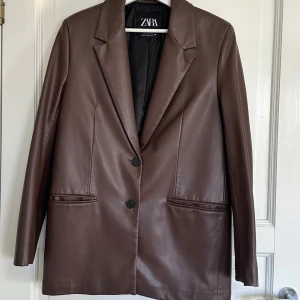Brun kavaj från Zara skinn - Snygg brun kavaj från Zara i skinn material . Den har en klassisk design med två knappar framtill och långa ärmar. Perfekt för en stilren look 🤎🤎