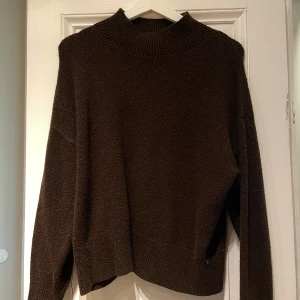 Brun stickad tröja - Mysig brun stickad tröja med ribbad krage och långa ärmar. Perfekt för kyliga dagar och enkel att matcha med olika outfits.