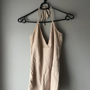 Beige haltertop från Samisu - Snygg halter top från Samisu med halterneck och djup v-ringning. Perfekt för varma dagar med sin lätta och bekväma passform. Enkelt att styla med olika accessoarer för en personlig touch.