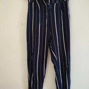 Randiga byxor med hög midja - Snygga randiga byxor i mörkblått med vita och bruna ränder. De har en hög midja.