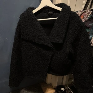 Svart teddyjacka från Gina Tricot - Säljer denna jätte populära mysiga  teddyjacka från Gina Tricot i storlek XS. Perfekt för kyliga dagar när du vill hålla dig varm och stilren.
