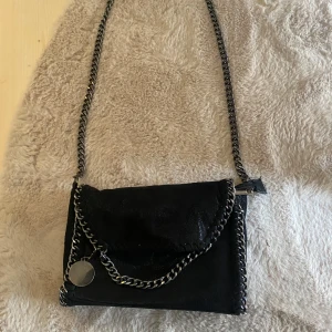 Svart axelväska med kedjedetaljer - Säljer denna jättefina väska som är så lik Stella McCartney! Fullt fungerade med dragkedja och inga defekter! Skriv om ni har frågor annars är det bara att trycka på ”köp nu” 💞💞💞