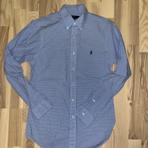 Blå skjorta från Polo Ralph Lauren - Snygg blå rutig skjorta från Polo Ralph Lauren i slim fit. Skjortan har stl S