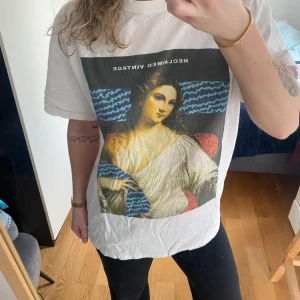 Vit t-shirt från Reclaimed Vintage - Säljer en vit t-shirt från Reclaimed Vintage med ett coolt Mona Lisa-tryck i färg. T-shirten är gjord av bomull och i storlek medium