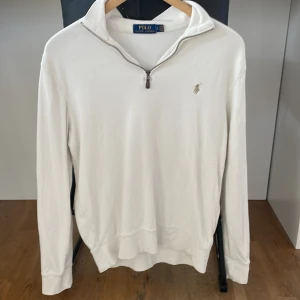 Vit långärmad half sip från Polo Ralph Lauren - Säljer en stilren vit långärmad half sip tröja från Polo Ralph Lauren med dragkedja vid halsen och det klassiska logotypbroderiet på bröstet. Perfekt för en avslappnad och elegant look.