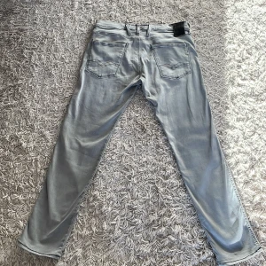 Grå jeans från Replay anbass - Säljer ett par snygga grå jeans från Replay. De har en klassisk femficksdesign och en stilren look. Perfekta för en avslappnad stil. Märkeslappen sitter på baksidan av midjan.
