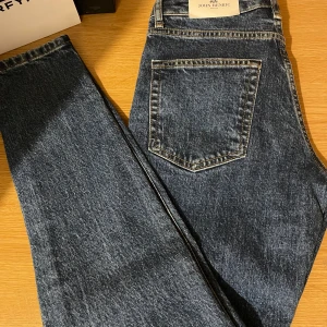 Blå jeans från John Henric - Snygga blå jeans från John Henric med klassisk design. Tillverkade av 79% ekologisk bomull, 20% återvunnen polyester och 1% lycra för en bekväm passform. Perfekta för en stilren look. Helt nya