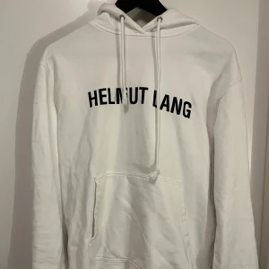 Vit hoodie från Helmut Lang - Säljer en stilren vit hoodie från Helmut Lang med svart text på framsidan.  Riktigt snygg passform och toppen skick! Strl S men sitter mer som en M. Hör av er vid andra frågor eller funderingar.