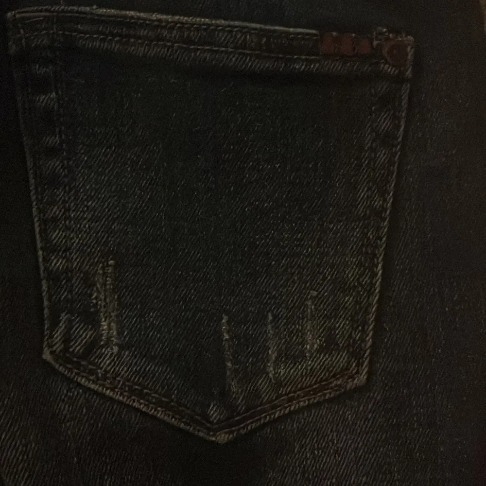 Snygga svarta bootcut jeans med färgglatt blommigt broderi på ena benet. Jeansen har en klassisk femficksdesign och är tillverkade i ett robust denimtyg. Perfekta för att ge din outfit en unik touch.. Farkut & Housut.