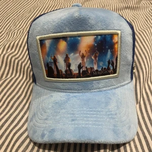 Maggiore velvet keps  - Snygg blå keps med ett färgglatt tryck framtill. Kepsen har ett nätmaterial på sidorna och baksidan för extra ventilation. Märket Maggiore syns på insidan av kepsen. Perfekt för en avslappnad stil.