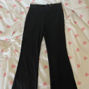 Svarta byxor med utsvängda ben - Säljer ett par svarta byxor med en snygg utsvängd stil. De är perfekta för både vardag och fest. Byxorna har en enkel design utan mönster och är gjorda i ett bekvämt material. Passar perfekt till en stilren outfit!