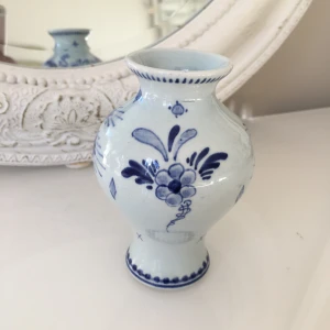 Blåvit vas från Delft - Charmig liten vas i klassisk blåvit design från Delft, Holland. Vasen har ett vackert blommönster och en elegant form som passar perfekt som dekoration i hemmet. Den är märkt i botten med 'Delft' och andra detaljer..höjd:11cm .4,03dim.