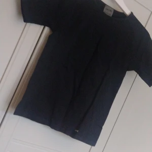 Svart t-shirt från Aim'n - Säljer en stilren svart Tränings Top från Aim'n. Den är NY "Utan prislapp"  och perfekt för vardagsbruk. Tränings Toppen har en normal passform och är kortärmad, vilket gör den idealisk för sommaren. Materialet känns mjukt och bekvämt mot huden. Strl