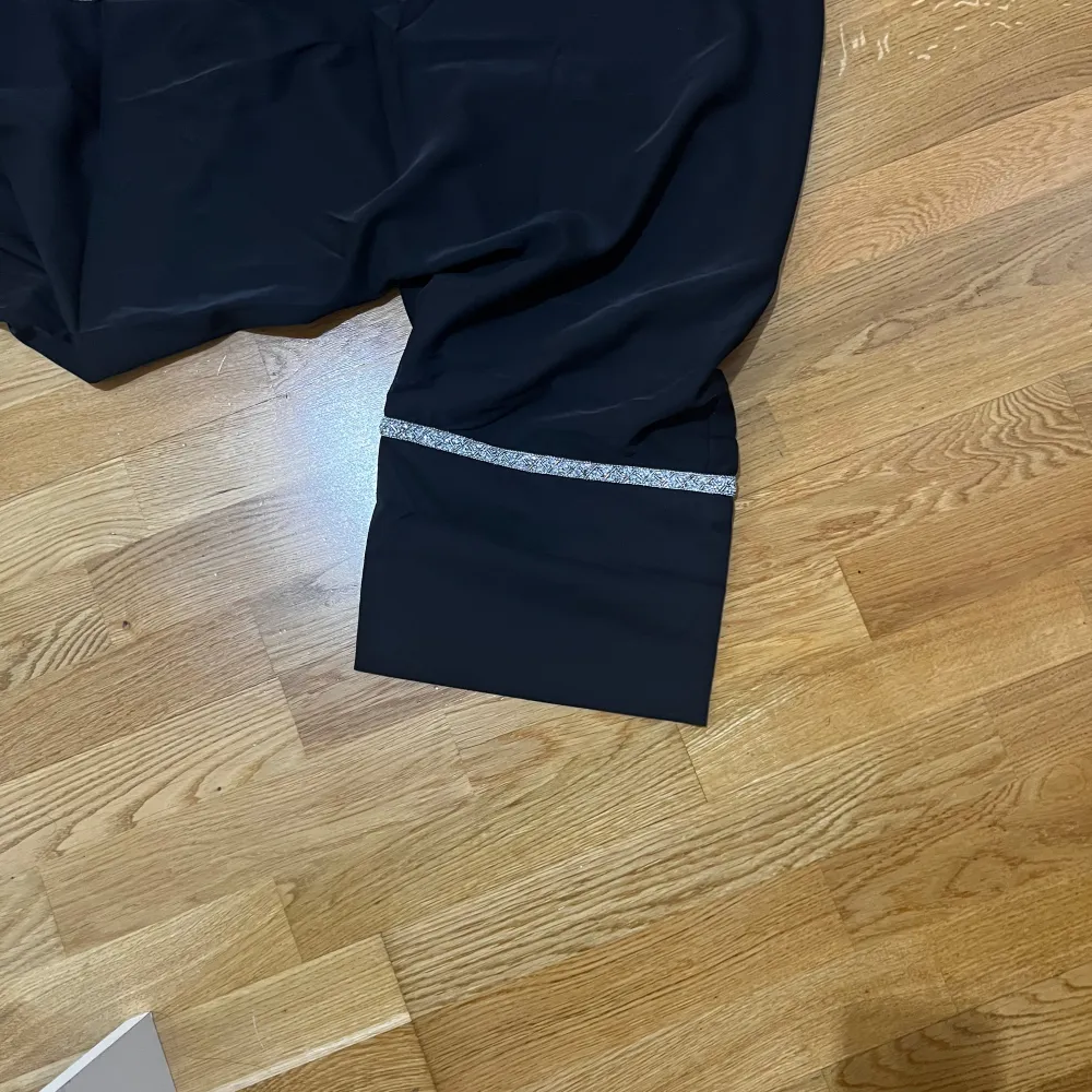 En svart öppen abaya med silver stenar, paljetter och glitter detaljer längs med kanterna och armarna. Den är en helt ny produkt med prislappen på. Helt o använd och den är i storlek S. Men den funkar absolut till större storlekar också då den är lit. Mekot.