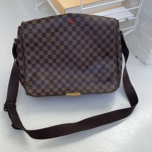 Louis Vuttion väska  - Axelremsväska för större laptop från Louis Vuttion. Inköpt för 12-13 år sedan. Väl använd med slitage. Inte använd senaste 8 åren.  Måtten 40 cm på längd, 30 cm höjd och va 13 cm bredd. 