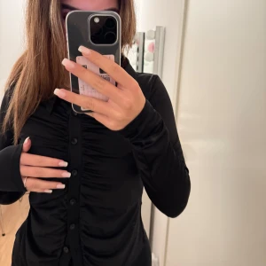 Svart topp från Nelly  - En söt topp från Nelly med skrynkliga detaljer som formar kroppen fint😍Strl M