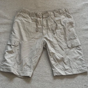 Beige shorts från Men's Classic - Säljer ett par bekväma och stilrena beige shorts från Men's Classic. De har en elastisk midja med snörning som går att justera och flera praktiska fickor, inklusive sidofickor med knappar. En knapp har åkt av (sista bilden) skriv om frågor!🤍