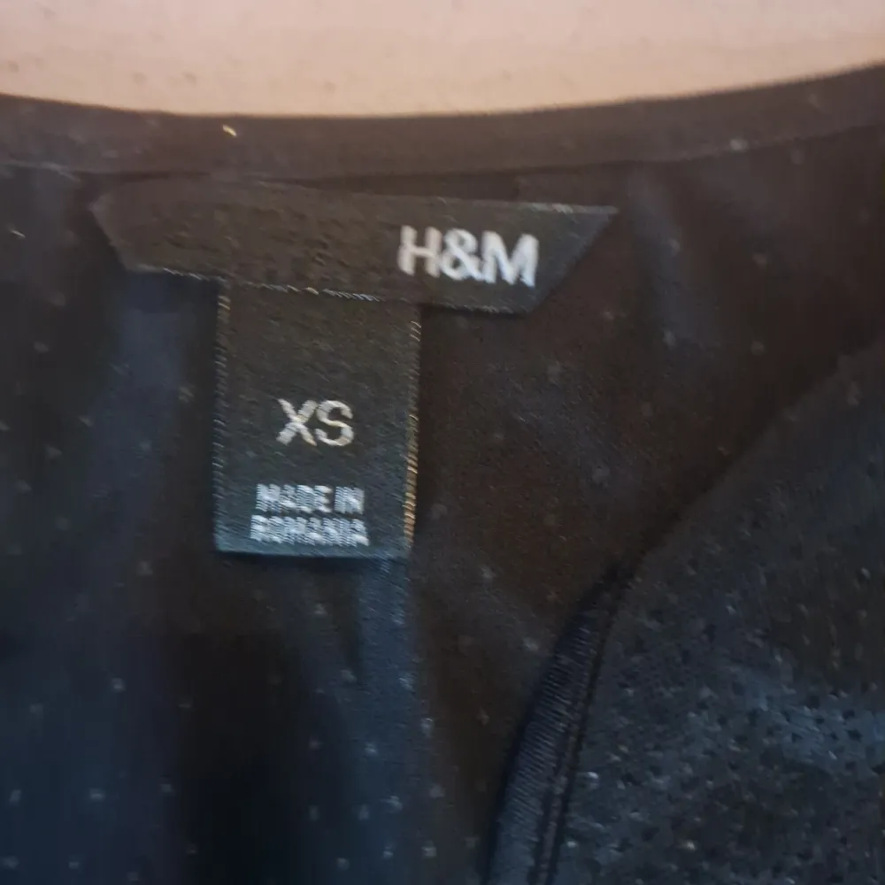 Säljer en snygg svart glittrig topp från H&M i storlek XS. Den är ärmlös och perfekt för festliga tillfällen. Toppen har en bekväm passform och är gjord i ett lätt material som glittrar fint i ljuset. Perfekt för att piffa upp vilken outfit som helst!. Toppar.