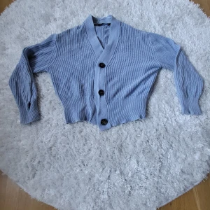 Grå stickad kofta från Lager 157 - Säljer en superfin grå stickad kofta från Lager 157. Den har en mysig och varm känsla med stora knappar framtill. Perfekt för höst och vinter när du vill hålla dig varm och snygg. Koftan är i storlek S och är gjord av 50% bomull och 50% akryl🩷