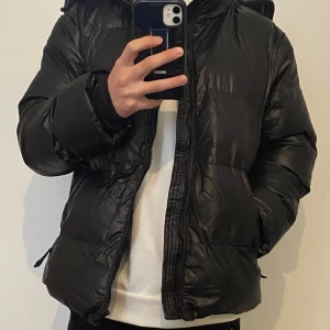 Svart Pufferjacka  - Snygg och stilren svart pufferjacka, perfekt för kallare dagar. Jackan är lättviktig men ändå varm, med en vadderad design som ger både komfort och skydd mot kyla. Jackan är och funkar som en ny. (Pris kan förhandlas).