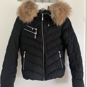 Hollies Jacka - Säljer min fina vinterjacka från Hollies. Jackan är  svart med silvriga kedjor och en superfin päls. Inga täcken på användning. Storlek 34/xs