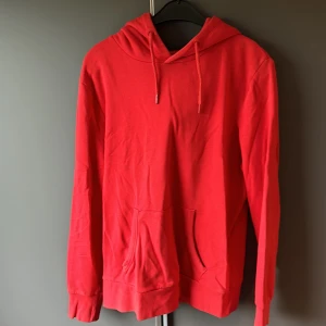 Röd hoodie - Säljer en snygg och bekväm röd hoodie. Perfekt för kyliga dagar eller när du bara vill mysa hemma. Den har en klassisk design med en stor ficka fram och justerbar huva. Passar till det mesta och är ett måste i garderoben!