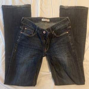 Säljer dessa mörkblåa, lågmidjade, bootcut jeans. De har en liten defekt nertill gylfen då den förra ägaren hade sytt om de. Innerbenslängden:78cm midjemått tvärs över: 34cm skriv privat för andra bilder och priset kan alltid diskuteras💕