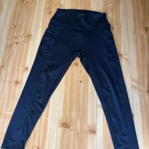 Svarta leggings med ficka - Säljer ett par mörkblå leggings som är perfekta för både träning och vardag. De har en praktisk ficka på sidan där du kan förvara mobilen eller andra småsaker. Leggingsen är högmidjade och sitter riktigt skönt på kroppen.